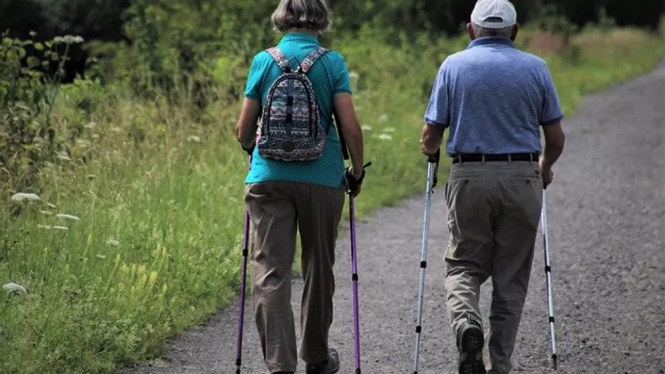 An elderly couple are walking with walking sticks. Photo