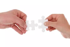 Two hands hold two pieces of a puzzle together. Photo